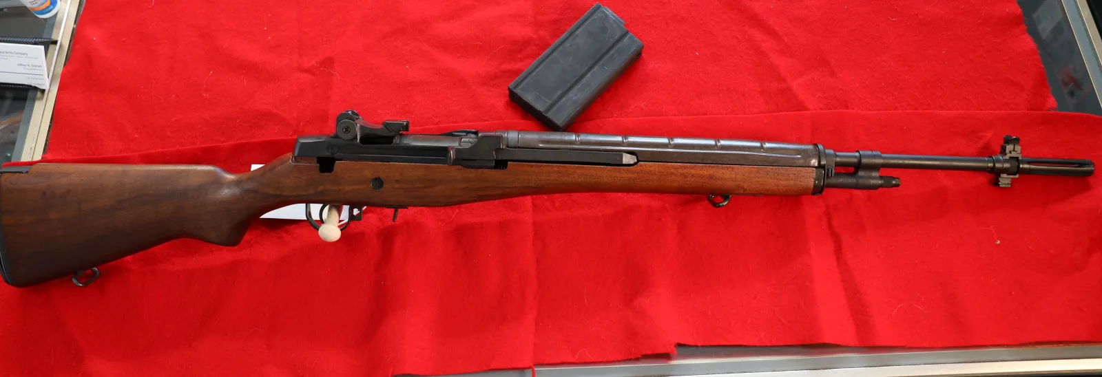 Wood-stocked M1A-style rifle with a magazine on red felt