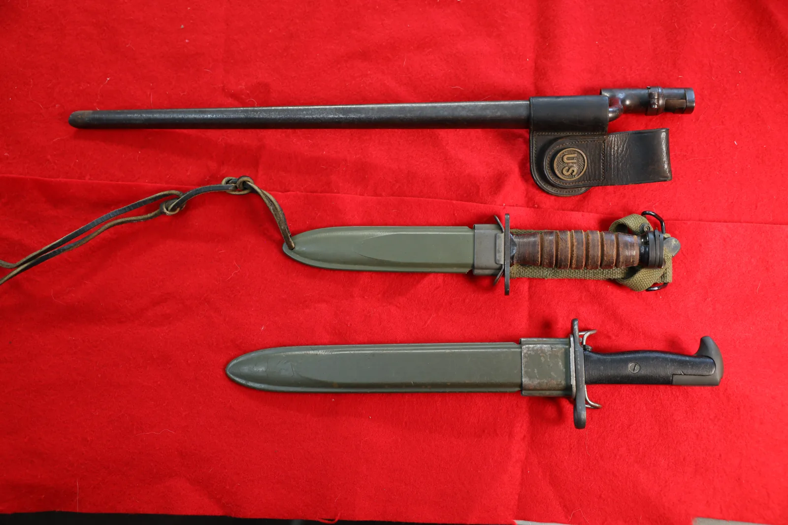 Three military bayonets and fighting knives with their scabbards