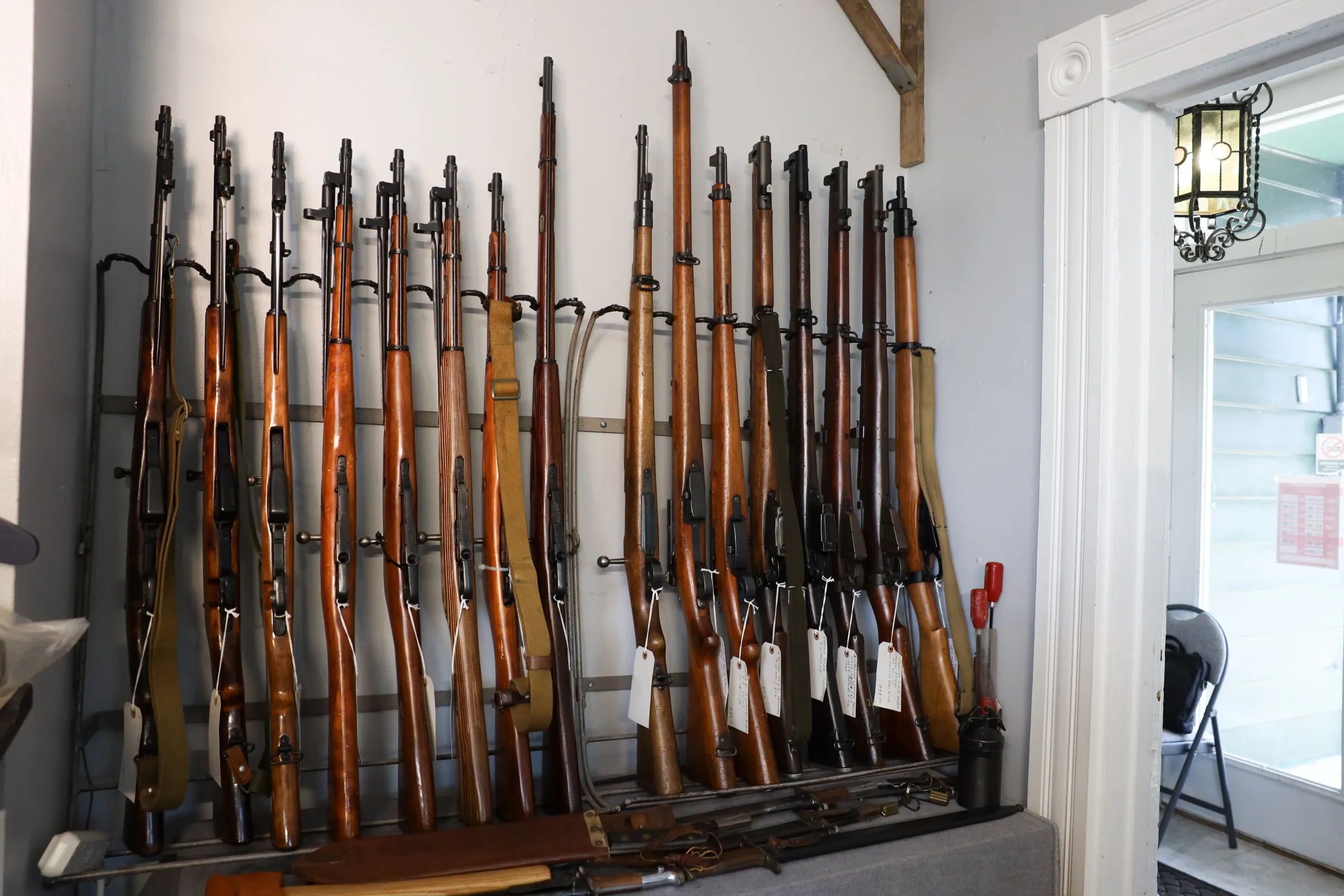 A long rack of wood-stocked military surplus rifles in the shop