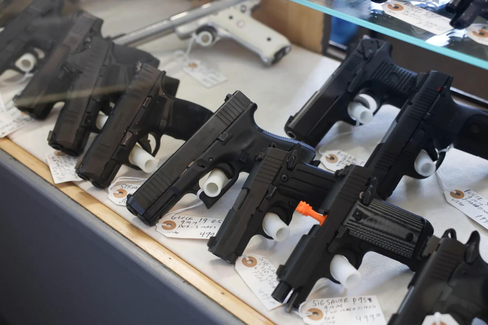 Modern semi-automatic pistols lined up in a glass display case