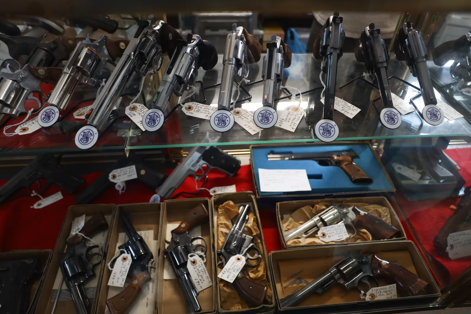 Smith & Wesson revolvers on a glass shelf above boxed vintage revolvers