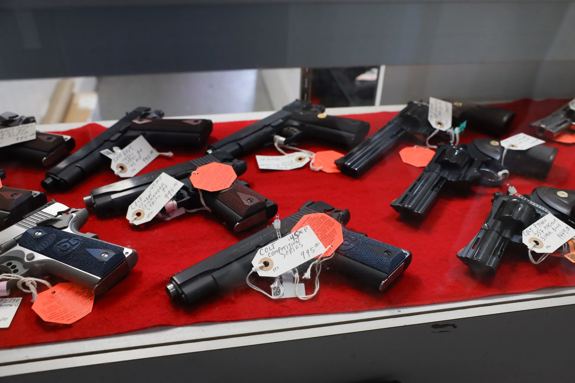 Handguns on red felt in the display case at Highland Arms Co in Ligonier, PA
